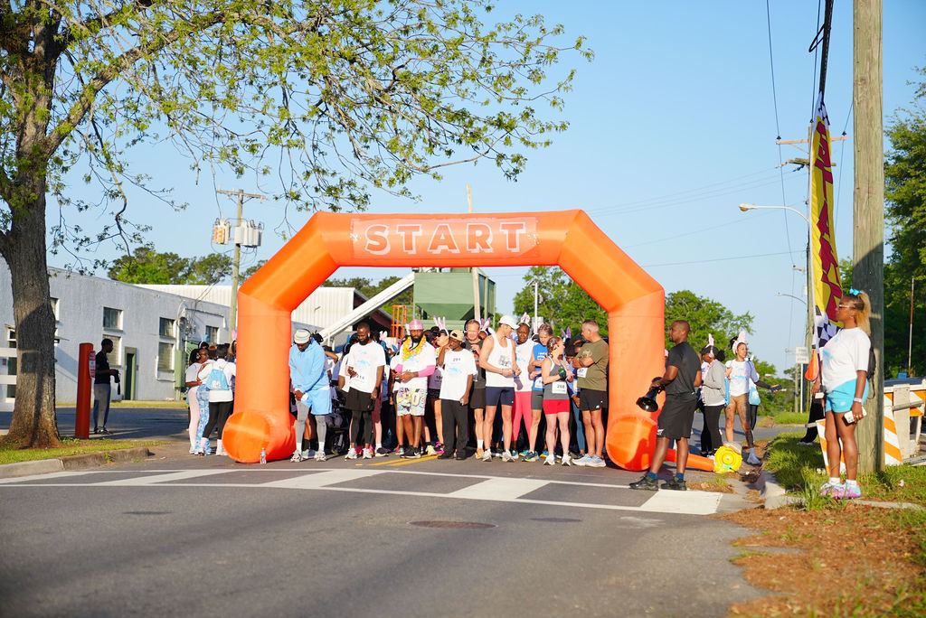 Wide view of the orange start arch and crowd at the 2025 run