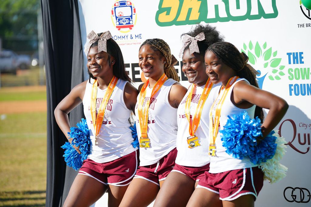Local cheerleaders with medals posing at the finish backdrop