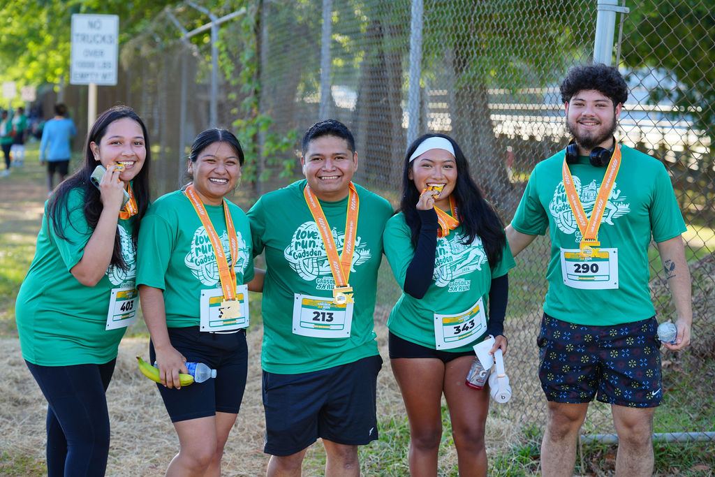 Five friends biting their medals and laughing together in 2026