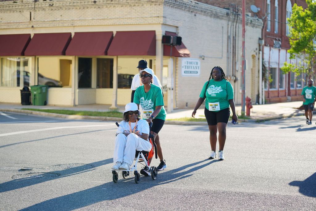 A participant pushes a loved one in a wheelchair across the course — everyone finishes together at the Gadsden 5K