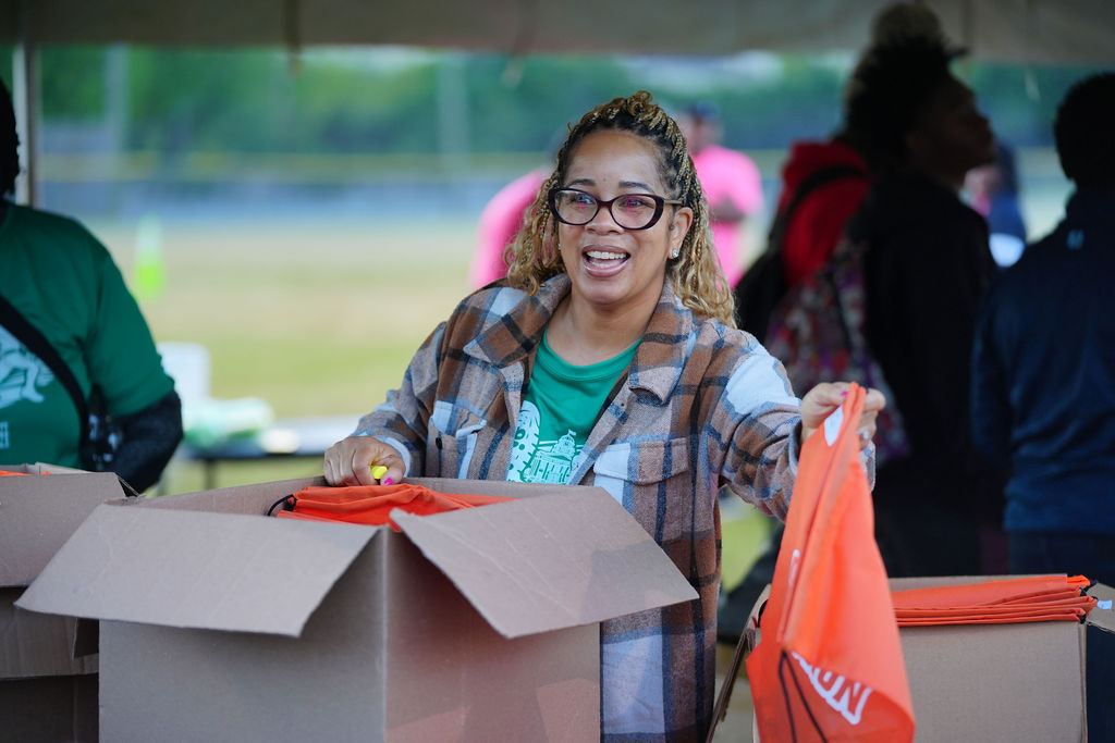A volunteer handing out race swag under the tent