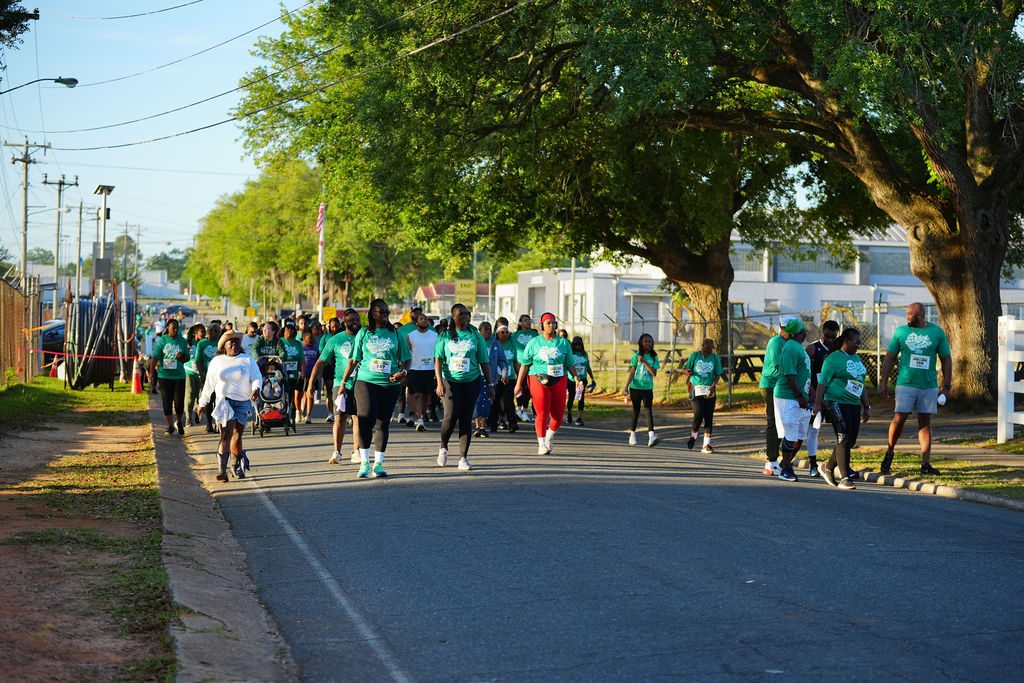 Hundreds of runners in green Gadsden 5K shirts filling a tree-lined street in Quincy, Florida